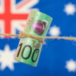Close up of an Australian one hundred dollar bill tied in string. Australian flag in background.