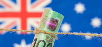 Close up of an Australian one hundred dollar bill tied in string. Australian flag in background.