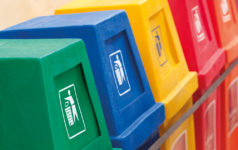 A row of recycling bins in different colors at a recycling station.